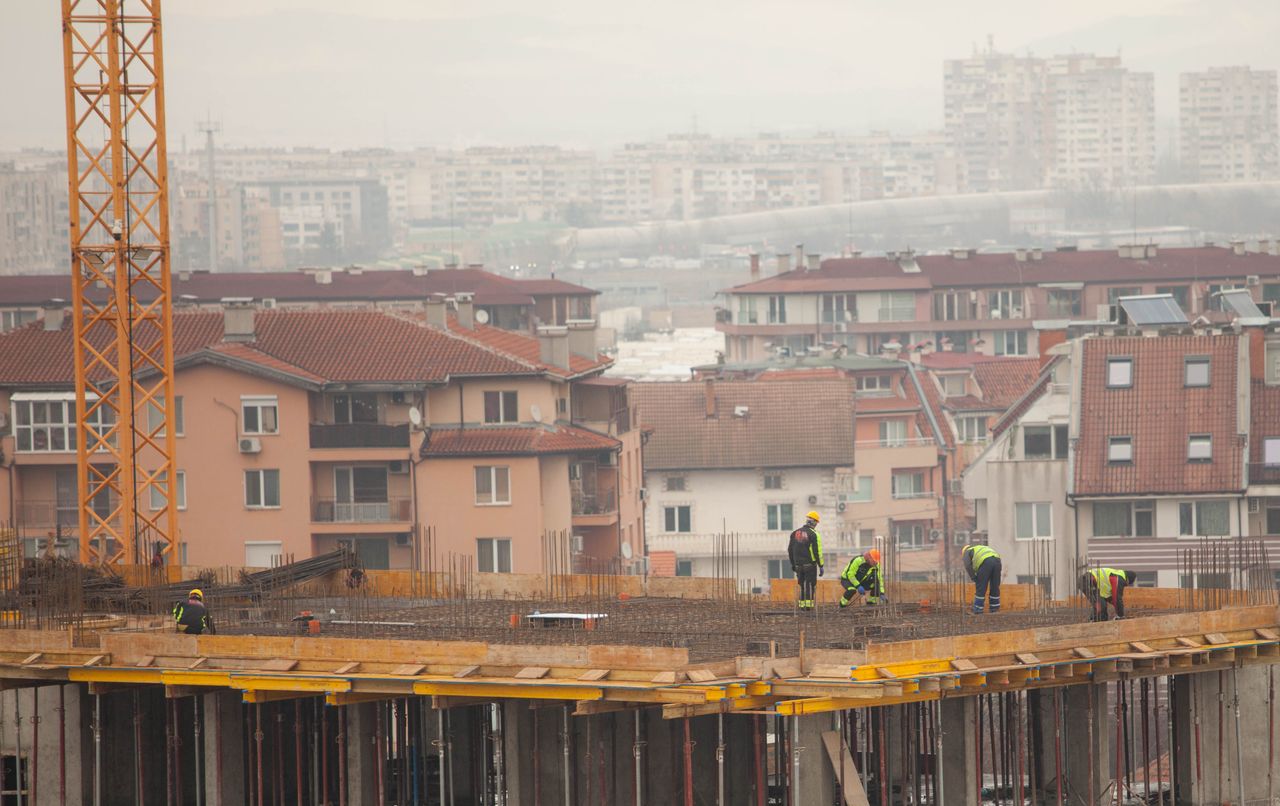 Workers at a city construction site with buildings in the background. Industrial urban development scene.