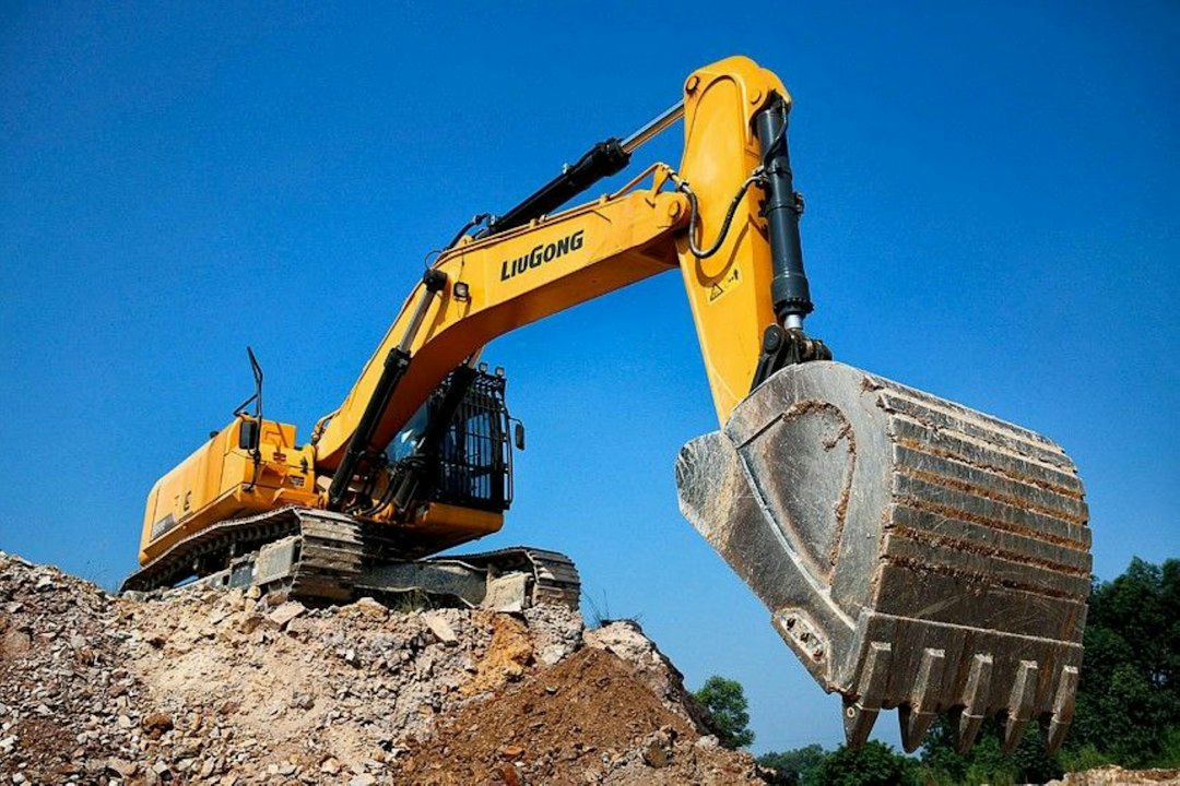 yellow-excavator-digging-dirt-against-a-blue-sky-oyi1n2ir52c